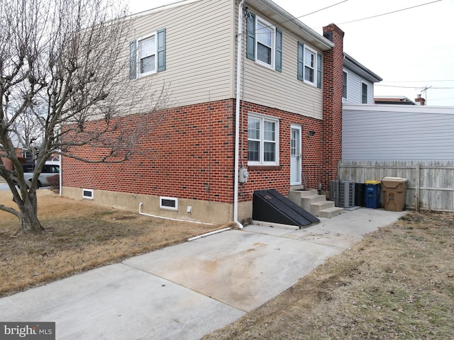 view of home's exterior featuring brick siding, a patio, and a lawn