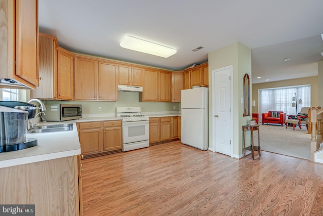 kitchen with under cabinet range hood, white appliances, visible vents, light wood-style floors, and light countertops