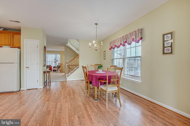 dining room with visible vents, baseboards, light wood-style floors, stairway, and an inviting chandelier