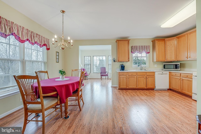 kitchen featuring white appliances, baseboards, light countertops, light wood-type flooring, and pendant lighting