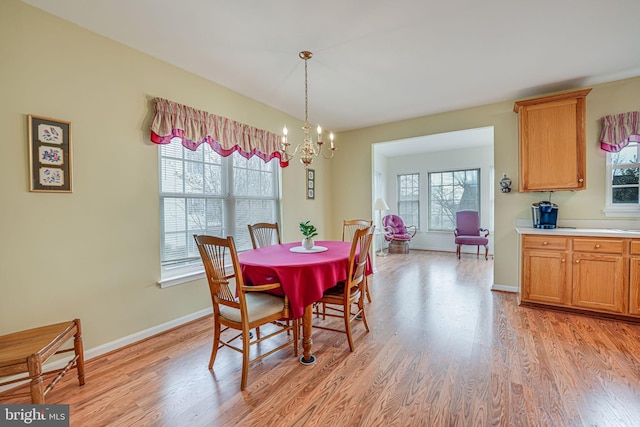 dining room featuring a chandelier, light wood finished floors, and baseboards