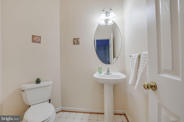 bathroom featuring toilet, baseboards, a sink, and tile patterned floors