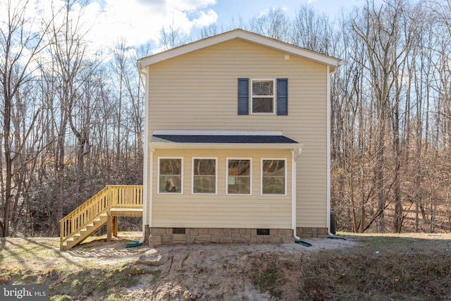 view of front of home with crawl space, a shingled roof, and stairway