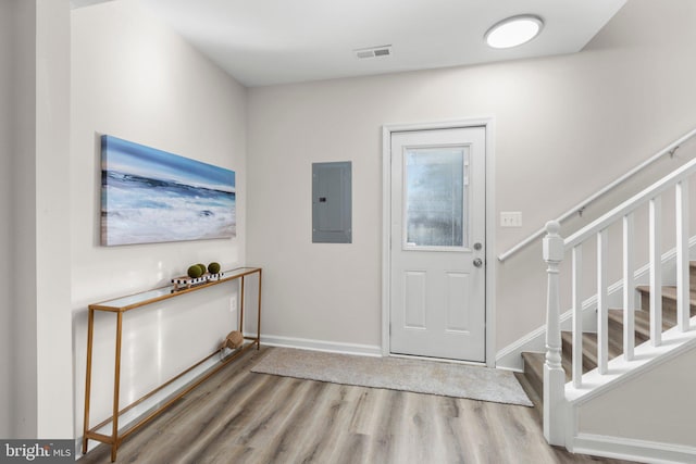 entryway with visible vents, stairway, wood finished floors, and electric panel