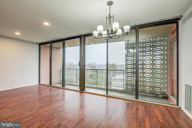 spare room featuring visible vents, a wall of windows, wood finished floors, and recessed lighting