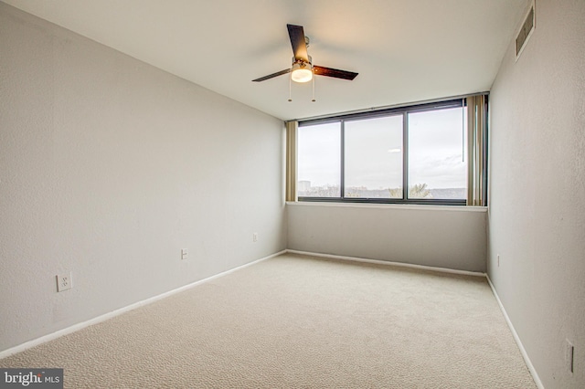 empty room with visible vents, carpet, a ceiling fan, and baseboards