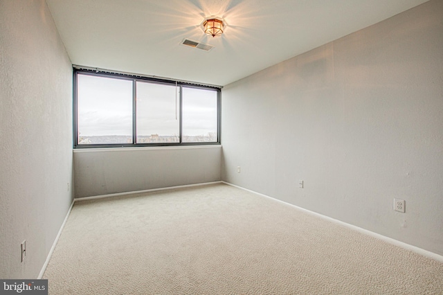 unfurnished room with carpet floors, visible vents, and baseboards