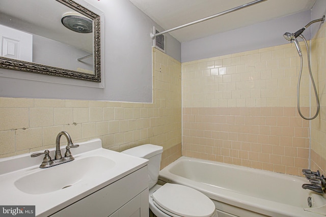 bathroom with visible vents, toilet, vanity, shower / washtub combination, and tile walls