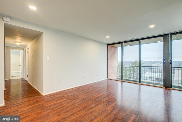 unfurnished room featuring expansive windows, baseboards, dark wood-style flooring, and recessed lighting