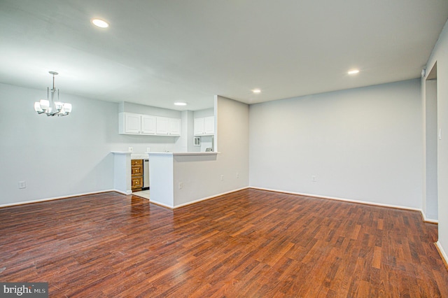 unfurnished living room with baseboards, an inviting chandelier, dark wood finished floors, and recessed lighting