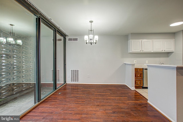 unfurnished dining area featuring dark wood-style floors, visible vents, a notable chandelier, and baseboards