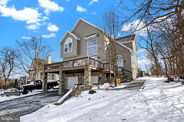 view of front of house with a deck, stone siding, and a garage