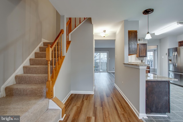 kitchen featuring visible vents, baseboards, stainless steel refrigerator with ice dispenser, wood finished floors, and hanging light fixtures