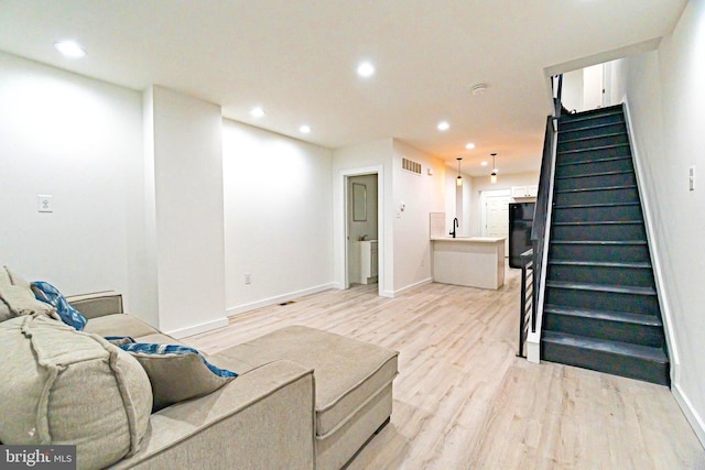 living area with visible vents, baseboards, light wood-style flooring, stairway, and recessed lighting