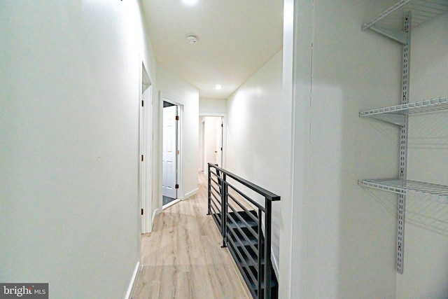 hall with recessed lighting, light wood-type flooring, an upstairs landing, and baseboards