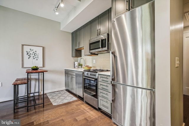 kitchen with light wood finished floors, stainless steel appliances, light countertops, backsplash, and baseboards