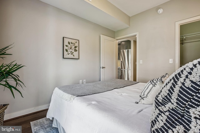 bedroom with a closet, dark wood finished floors, and baseboards