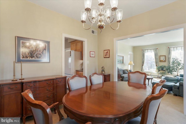 dining space with a chandelier, light colored carpet, and visible vents