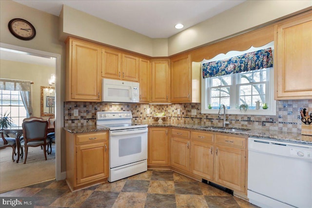 kitchen with white appliances, stone counters, a sink, and backsplash