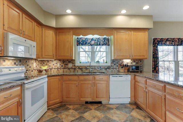 kitchen featuring light stone counters, white appliances, a sink, tasteful backsplash, and stone finish floor