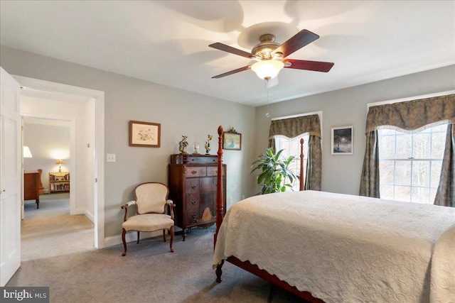 bedroom featuring baseboards, multiple windows, a ceiling fan, and light colored carpet