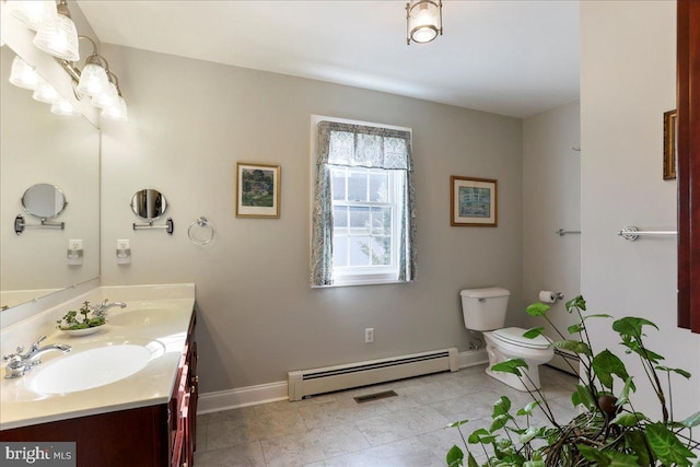 bathroom featuring double vanity, a baseboard heating unit, toilet, and a sink