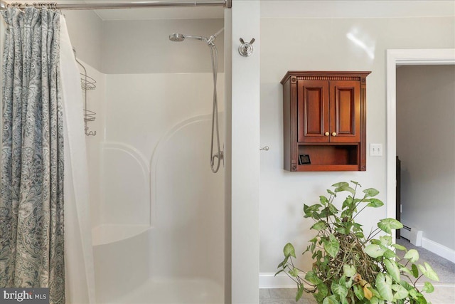 bathroom with a baseboard heating unit, a shower stall, and baseboards
