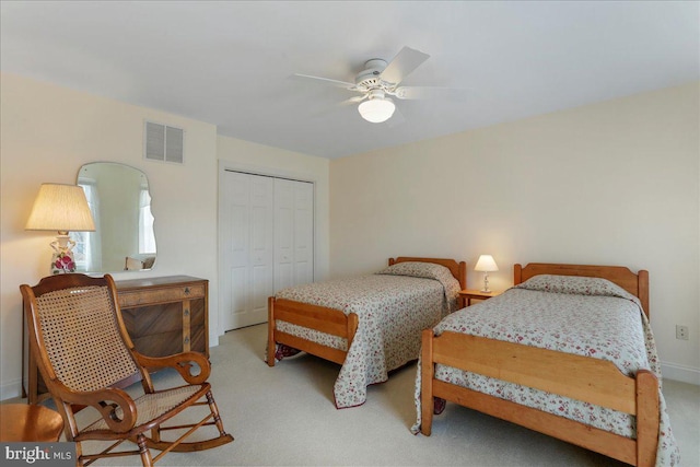 bedroom with a closet, visible vents, ceiling fan, and light carpet