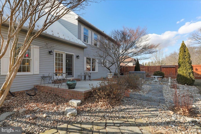 back of house featuring metal roof, a patio area, fence, and a hot tub