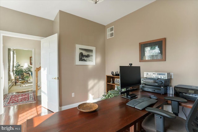 office space featuring baseboards, visible vents, and wood finished floors