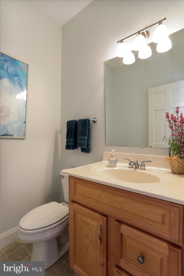 half bathroom with toilet, vanity, and tile patterned floors