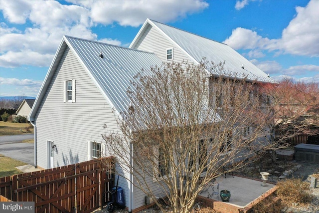 view of side of property featuring metal roof and fence