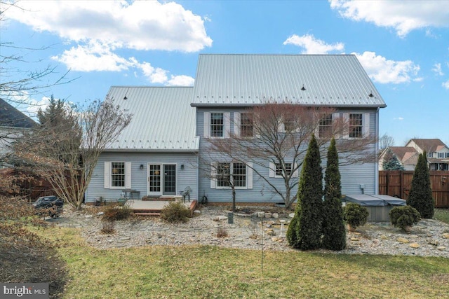 rear view of property featuring a lawn, a hot tub, a patio area, metal roof, and fence