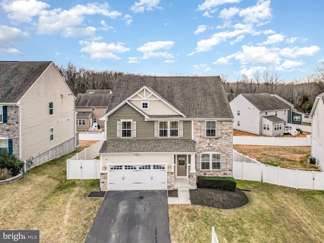 view of front of property with stone siding, a gate, fence private yard, and driveway