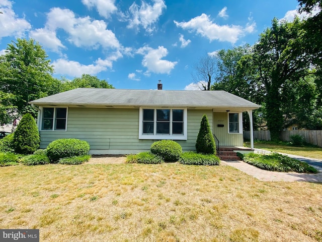 single story home featuring a chimney, a front yard, and fence