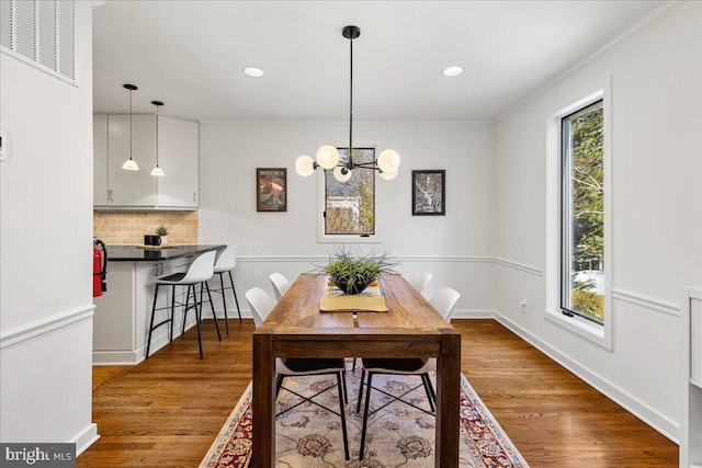 dining room featuring baseboards, plenty of natural light, visible vents, and wood finished floors