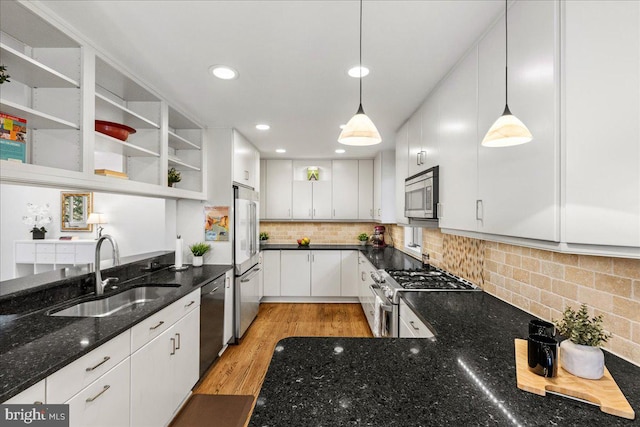 kitchen with light wood finished floors, white cabinets, appliances with stainless steel finishes, open shelves, and a sink