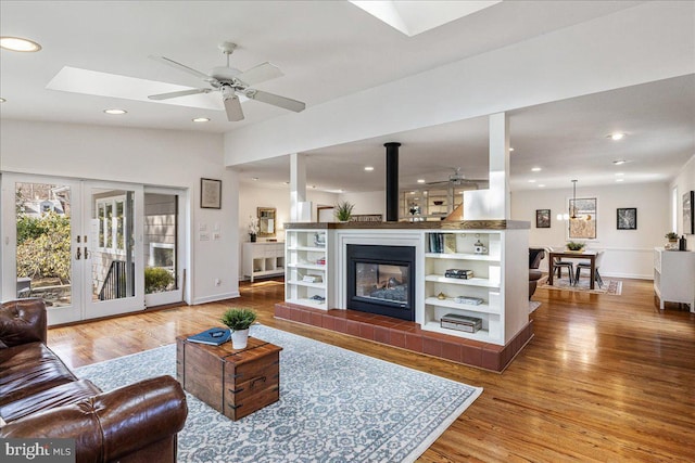 living room with recessed lighting, a fireplace, wood finished floors, and french doors