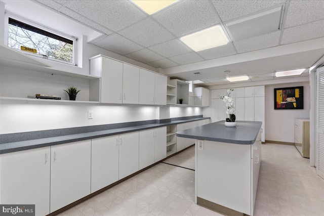 kitchen with open shelves, light floors, dark countertops, and white cabinetry