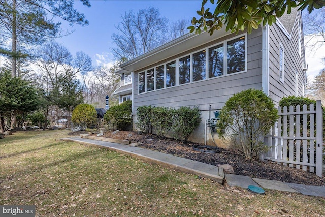 view of property exterior with fence and a lawn