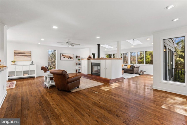 living area featuring recessed lighting, a skylight, baseboards, and wood finished floors