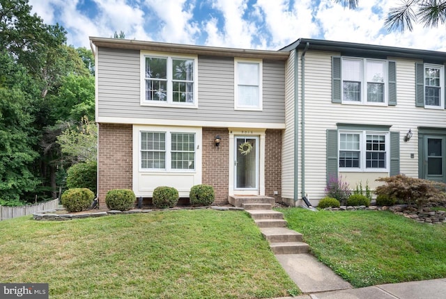 view of front of home featuring brick siding, a front lawn, and fence