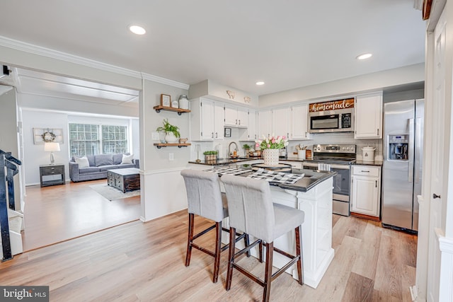 kitchen with tasteful backsplash, dark countertops, stainless steel appliances, light wood-type flooring, and white cabinetry