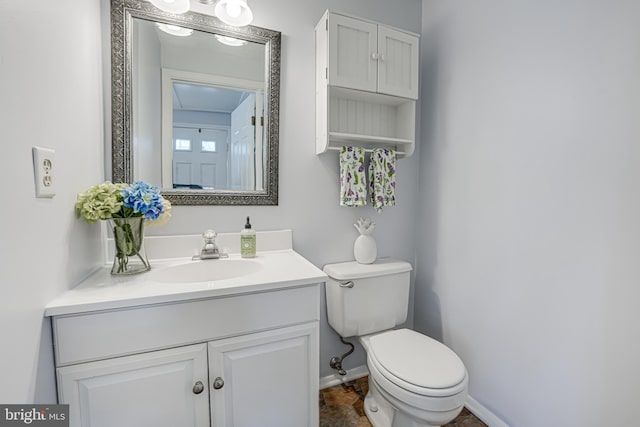 bathroom featuring baseboards, vanity, and toilet