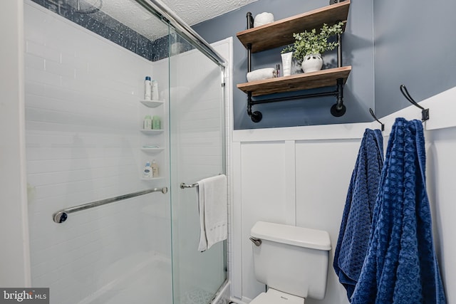 bathroom featuring a textured ceiling, a shower stall, and toilet