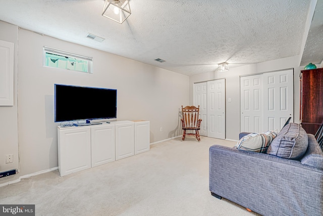 carpeted living area featuring a textured ceiling, visible vents, and baseboards