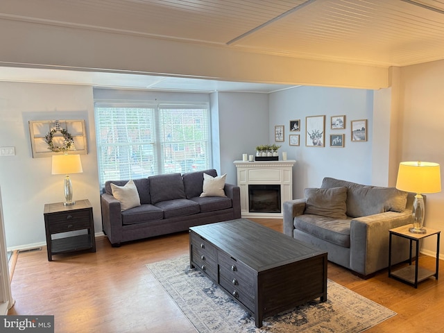 living area featuring visible vents, a fireplace, baseboards, and wood finished floors