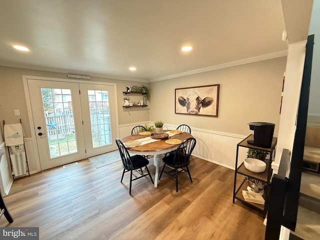 dining area with crown molding, visible vents, wood finished floors, and wainscoting