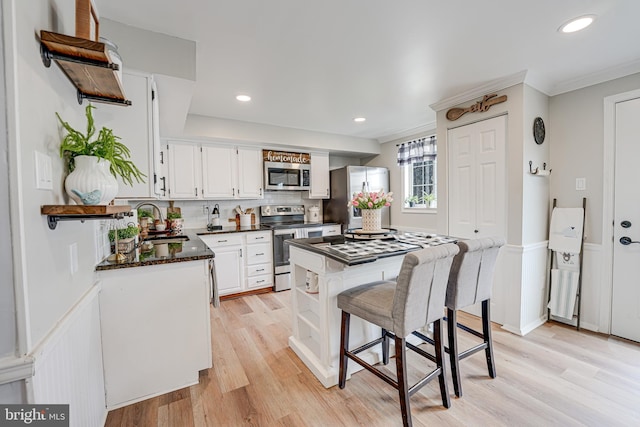 kitchen featuring white cabinets, appliances with stainless steel finishes, light wood-type flooring, open shelves, and a sink