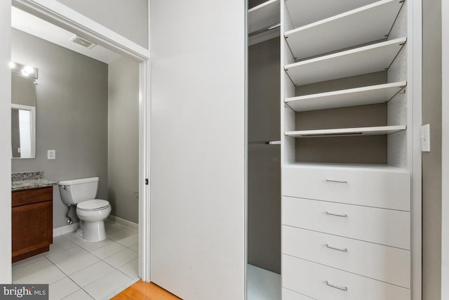 half bathroom featuring visible vents, toilet, vanity, tile patterned flooring, and baseboards